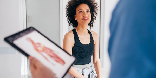 A woman in workout clothes listens attentively during a consultation.