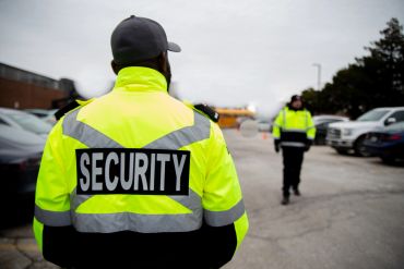 Security guard in bright yellow jacket at a parking lot.