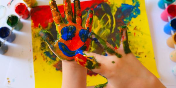 Child's hand painted with colorful smiley face.