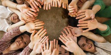 People forming a circle with their hands reaching towards the center.