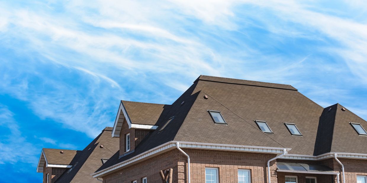 Brown brick houses under a bright blue sky with wispy clouds.