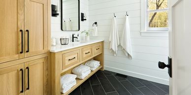 Bright bathroom with wooden cabinets and black floor tiles.