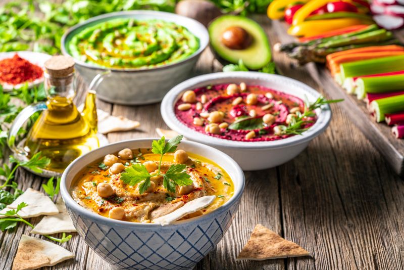 Hummus Three bowl of chickpeas, avocado and beetroot vegetables for dip on rustic wooden table board background and ingredients
