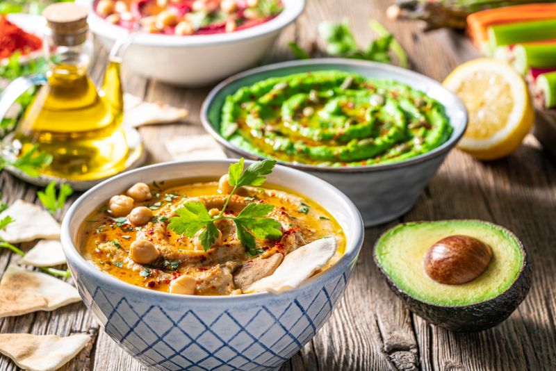 Hummus Three bowl of chickpeas, avocado and beetroot vegetables for dip on rustic wooden table board background and ingredients