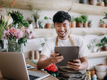 Smiling florist using a tablet in a flower shop.