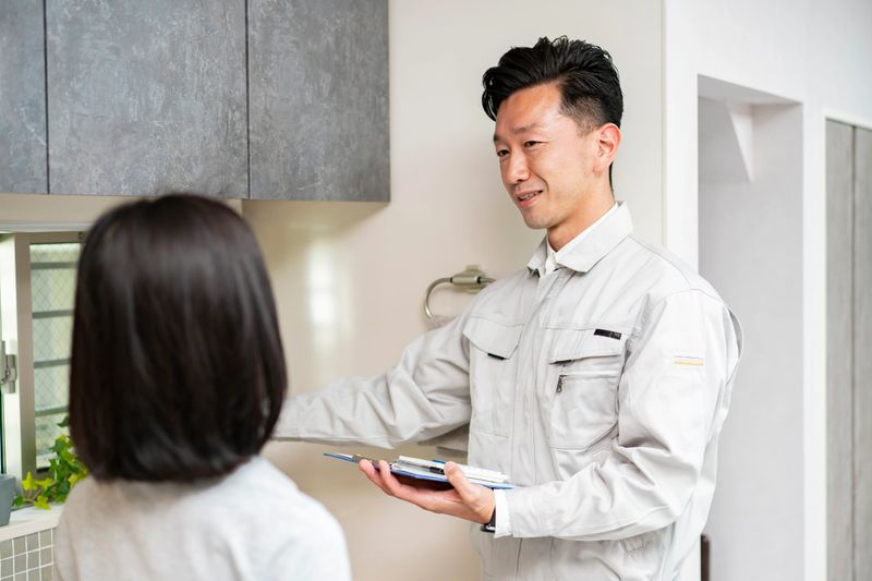 A man in work clothes explaining to a woman at kitchen (water supplier)