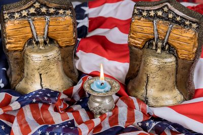 Two Liberty Bell replicas with a lit candle on American flags.