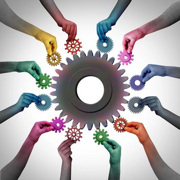 Multicolored hands holding small gears around a large central gear.