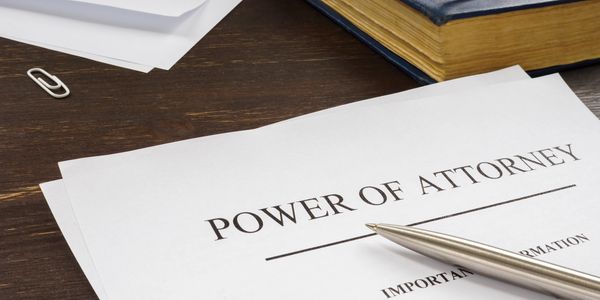 A pen on a Power of Attorney document on a wooden desk.