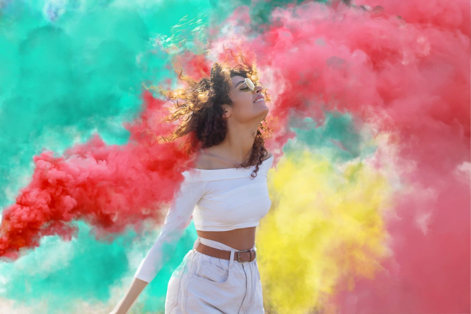Woman enjoying colorful smoke clouds with a joyful expression.