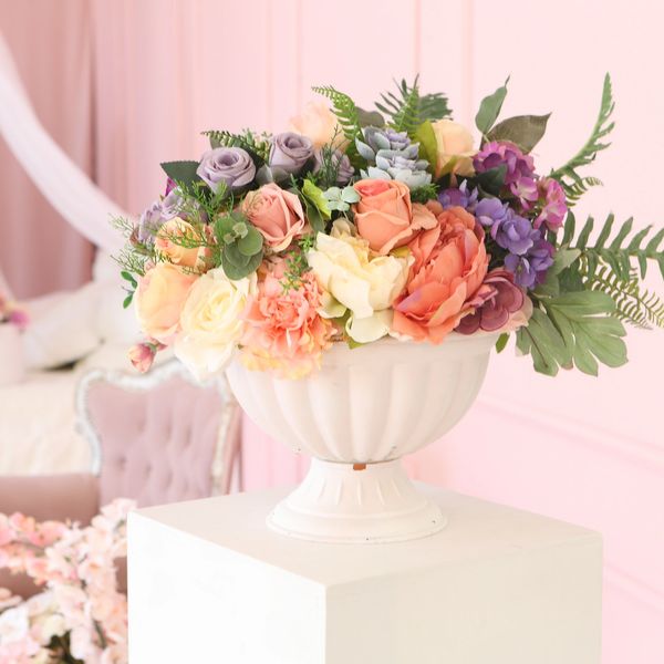 Elegant floral arrangement in a classic white vase on a pedestal.