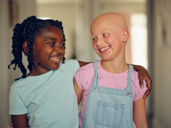 Two young girls smiling and embracing each other warmly indoors.
