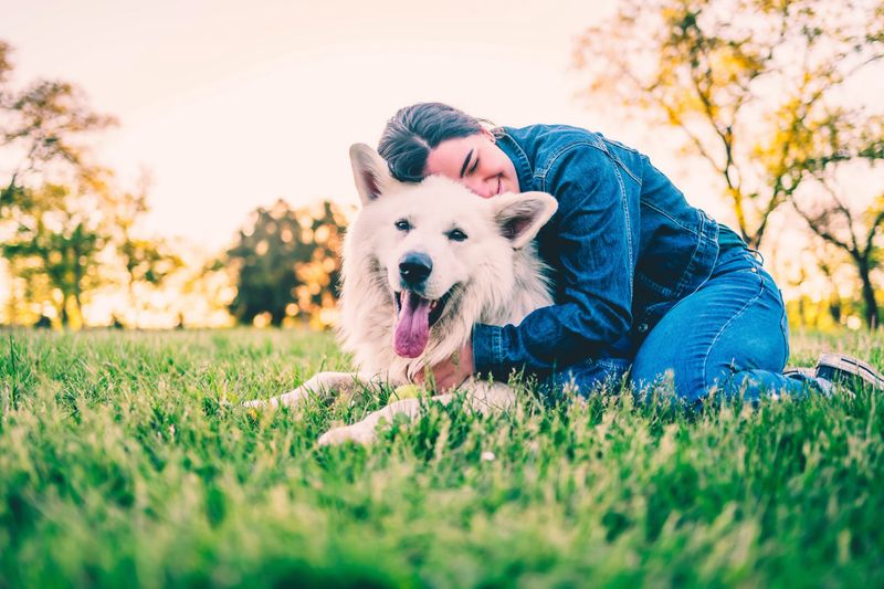 Young cheerful woman enjoying with her dog in the park
