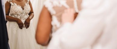 Bride in a detailed lace wedding dress looking at herself in the mirror.