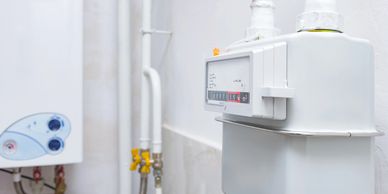 Close-up of a white gas meter installed on a wall with connected pipes.