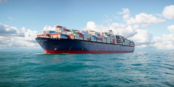 A large container ship loaded with colorful cargo containers sailing on the ocean.