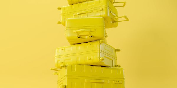 Stack of yellow suitcases against a yellow background.