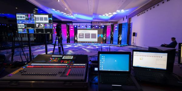 Control room setup for a multimedia event with screens and laptops.