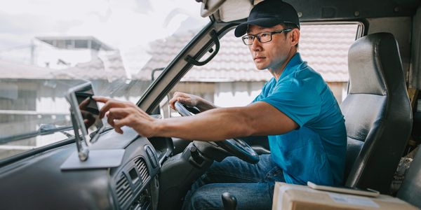 Delivery driver using GPS device inside truck cabin.