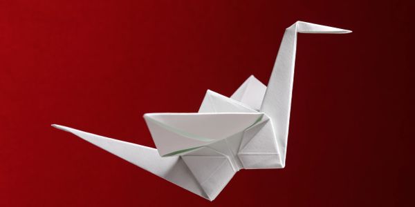 White origami crane against red background.