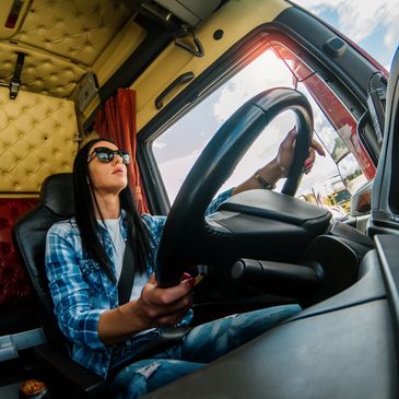 Woman confidently driving a large truck with focus and style.