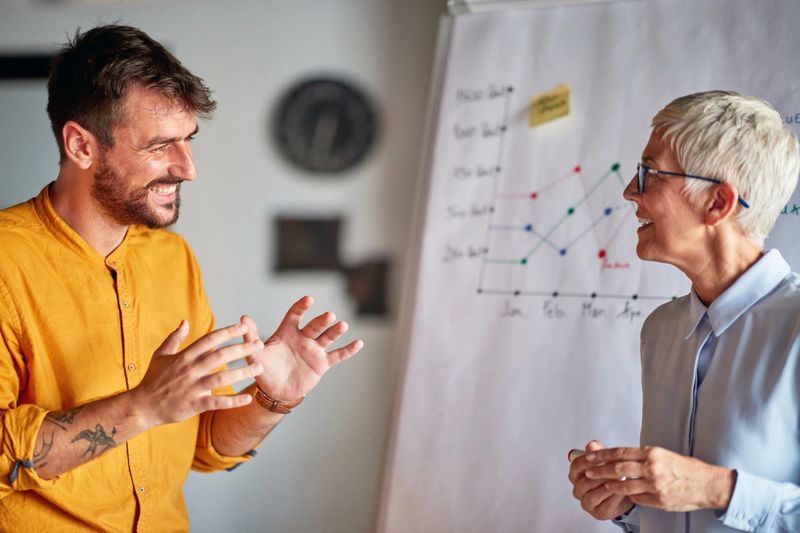 Senior female partner mentoring happy businessman in the office