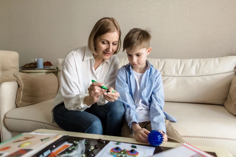 Adult woman and a teenager are sitting behind on the couch playing a board game. High quality photo