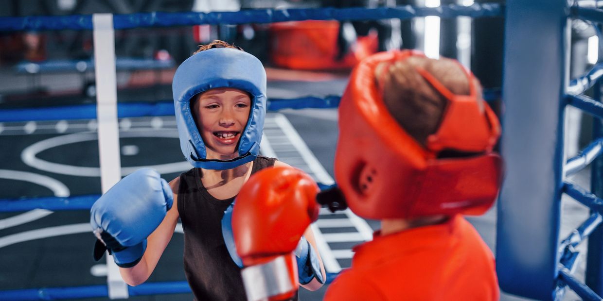 Two young boys having fun boxing with head protection gear.