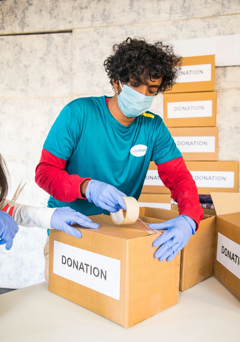 Volunteer busy packing donation boxes for donating - concept of Charity, Social work or service during coronavirus covid-19 pandemic lockdown