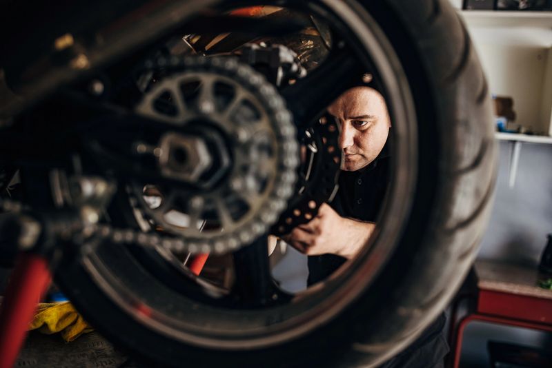 One man, male motorcycle mechanic repairing motorcycle in his workshop.