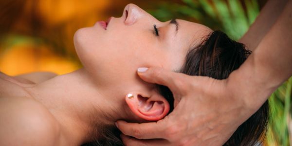 A woman receiving a head massage with closed eyes.