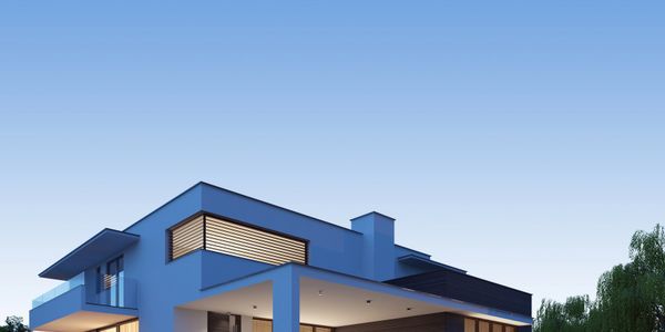 Modern two-story house with large windows glowing warmly at dusk.