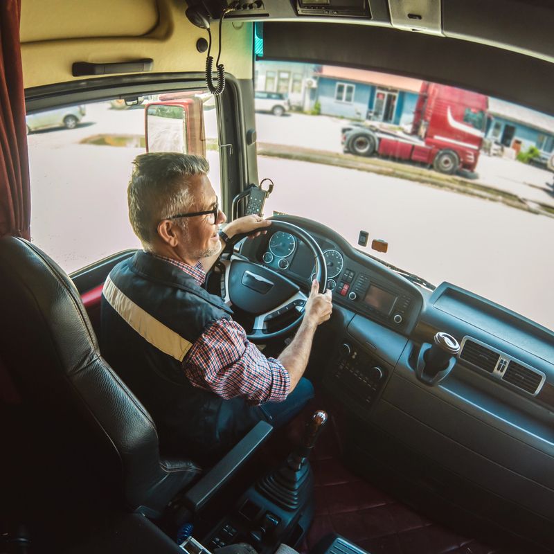 Professional mature truck driver driving truck vehicle.