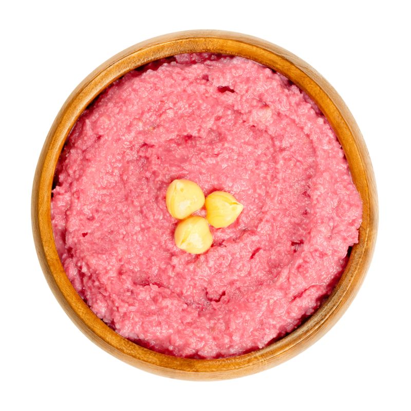 Beetroot hummus dip with chickpea garnish in a wooden bowl. Middle Eastern dip, spread or savory dish made of cooked, mashed chickpeas, blended with boiled beets, tahini, lemon juice and garlic. Photo