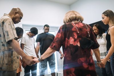 Group of people holding hands in prayer circle.
