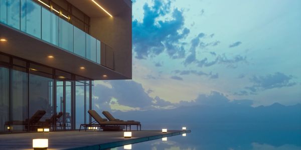 Modern house with infinity pool overlooking serene sunset sky.