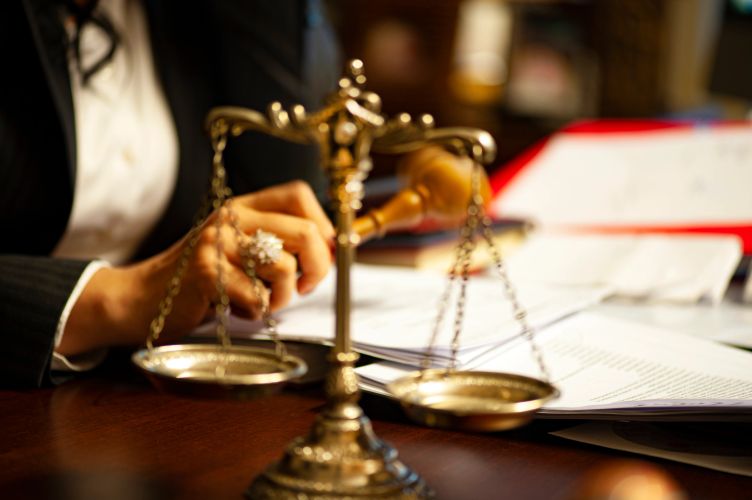 A judge with a gavel and scales of justice on a desk.