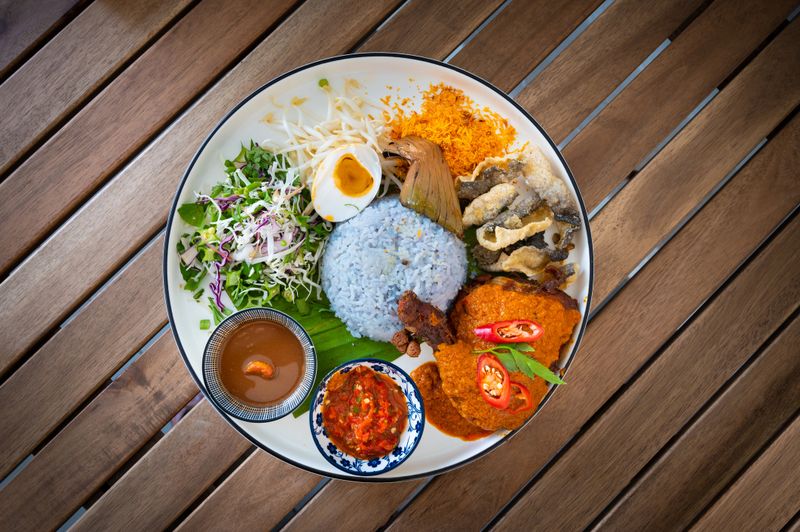 Nasi Kerabu is a type of Nasi Ulam and it’s a popular Malay rice dish especially at Kelatan State and Terengganu State of Malaysia. The blue color of rice is resulting from cooking the petals of Clitoria Ternatea flowers that commonly used as a natural food coloring in cooking it.