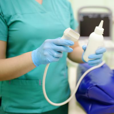 Medical professional holding an ultrasound probe and gel bottle.