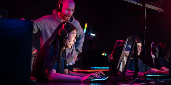 Gamers focused on their computer screens in a dimly lit room.