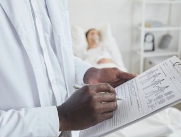 Doctor reviewing medical chart with patient in the background.