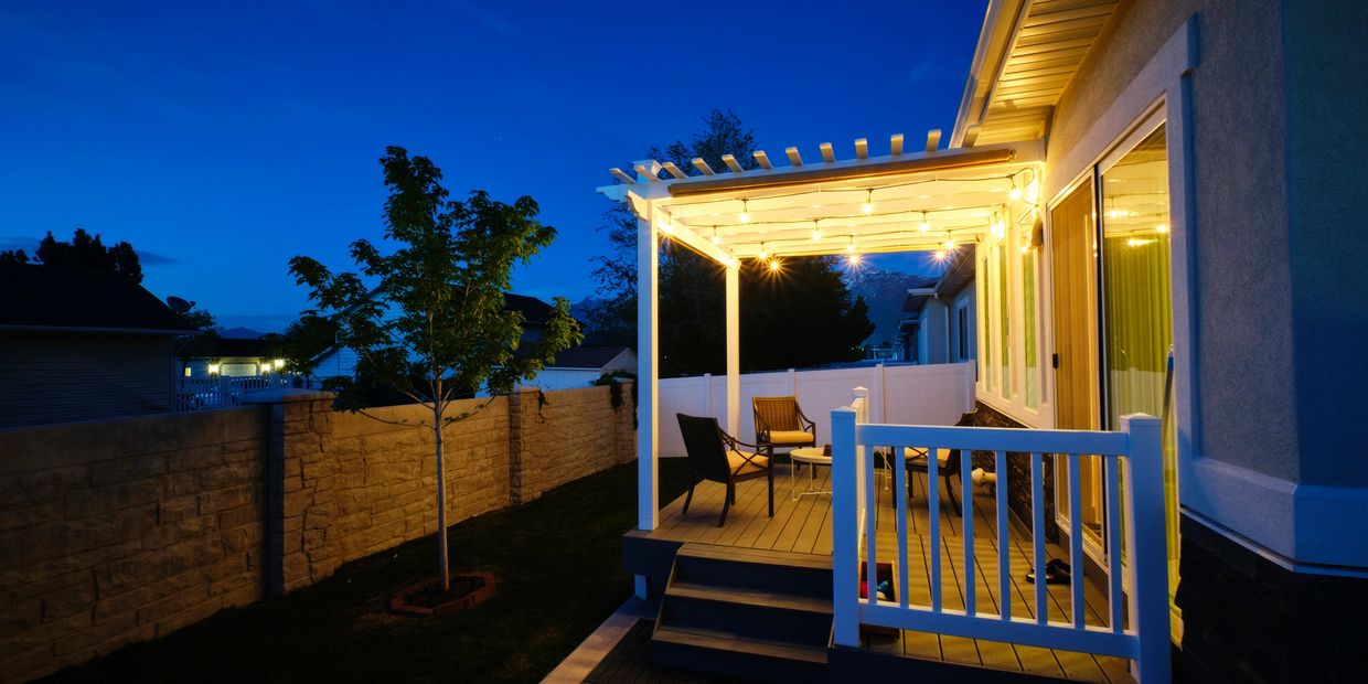 Cozy backyard patio with string lights glowing at dusk.