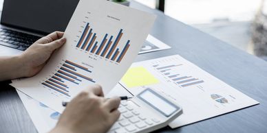 Person analyzing bar graphs with a calculator.