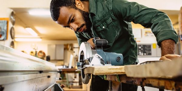 Man focused on cutting wood with a circular saw in a workshop.