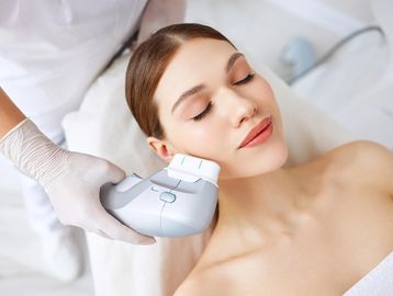 Woman receiving a skin treatment with a handheld device.