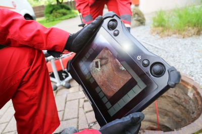 Person holding a device showing an underground inspection image.