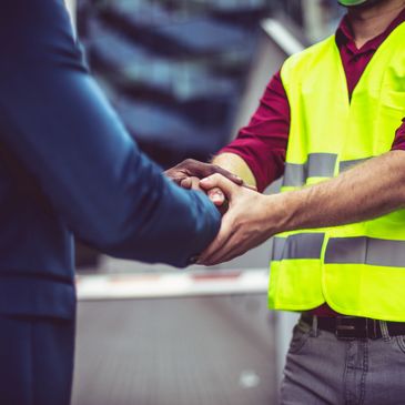 Two men shaking hands, one wearing a safety vest.