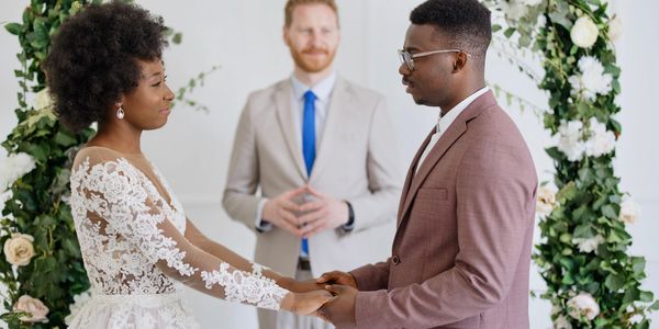 Couple holding hands during wedding ceremony with officiant in background.
