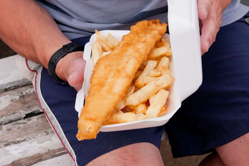 Man holding a portion of fish and chips fresh from the chip shop