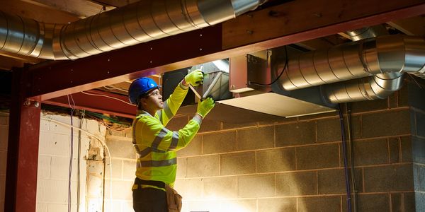 image of a HVAC installer putting in ductwork in the basement of a new custom home 